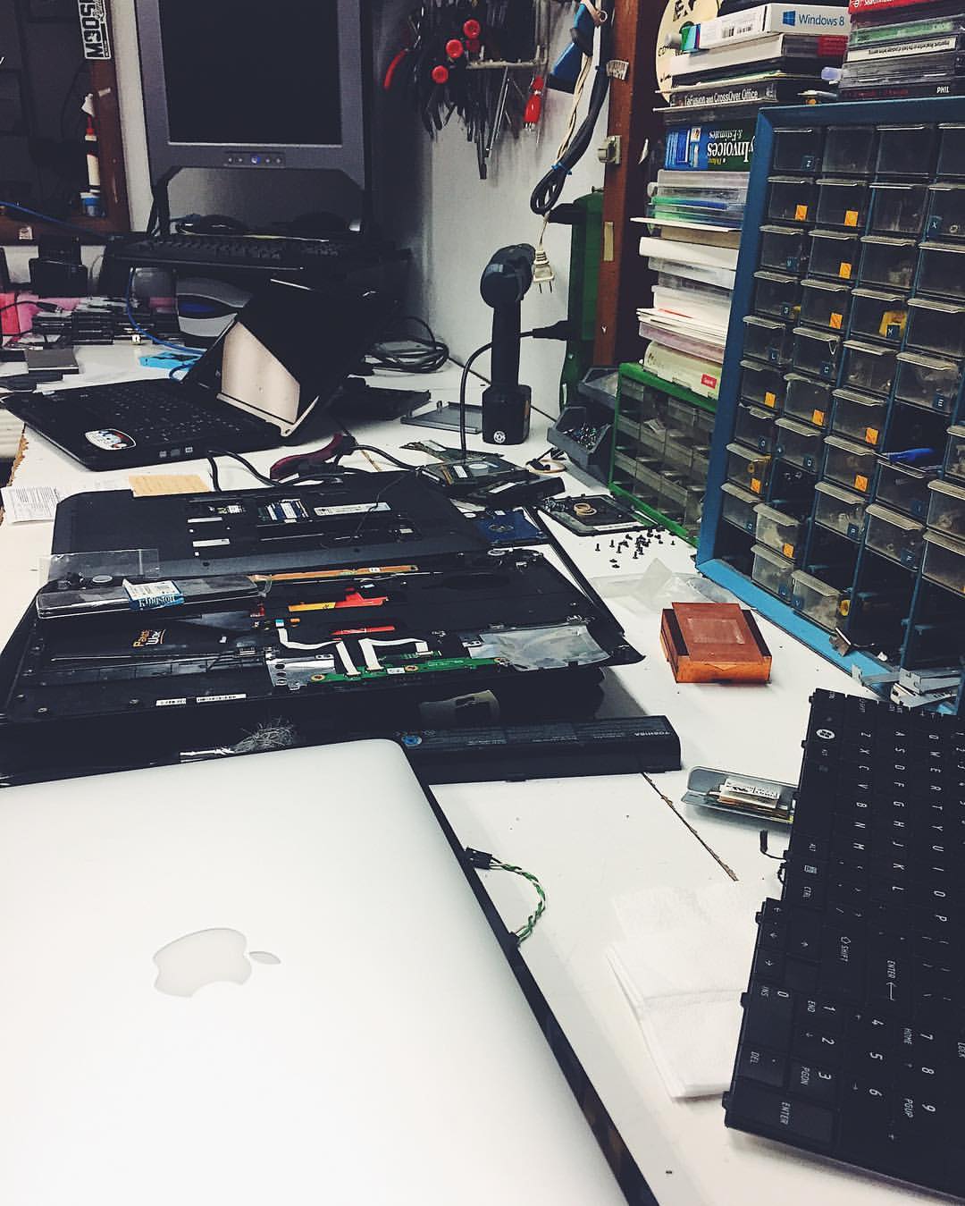 Laptop and computer parts laid out across a busy repair workshop bench