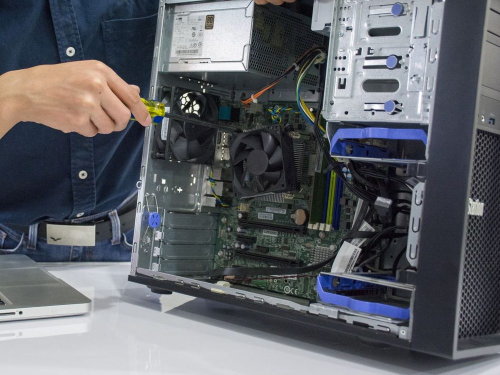 Technician working inside an open desktop computer tower